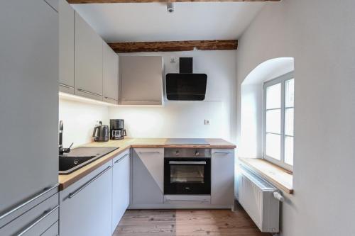 a kitchen with white cabinets and a sink and a window at FarmHouse Eckartsberg im Zittauer Gebirge - Ferienwohnung mit 2 Schlafzimmern, Terrasse und WALLBOX in Mittelherwigsdorf