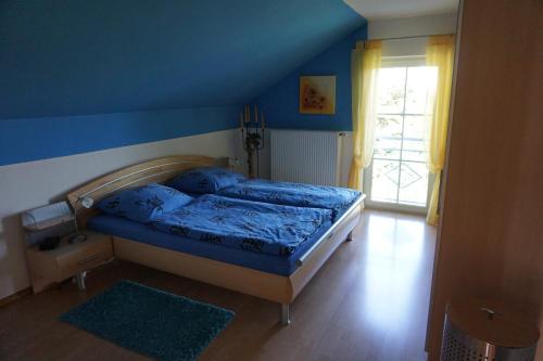 - une chambre avec un lit et un mur bleu dans l'établissement Ferienhaus Englburg in absolut ruhiger Lage, à Tittling