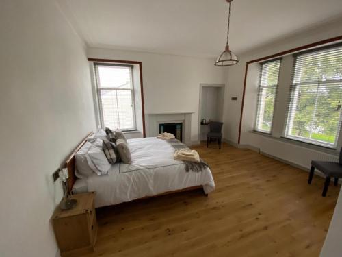 um quarto com uma cama com lençóis brancos e pisos em madeira em Manor House Hotel em Thurso