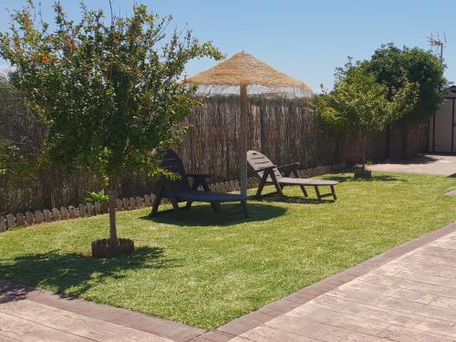 two park benches and a umbrella in a yard at Casa Prefabricada in El Palmar