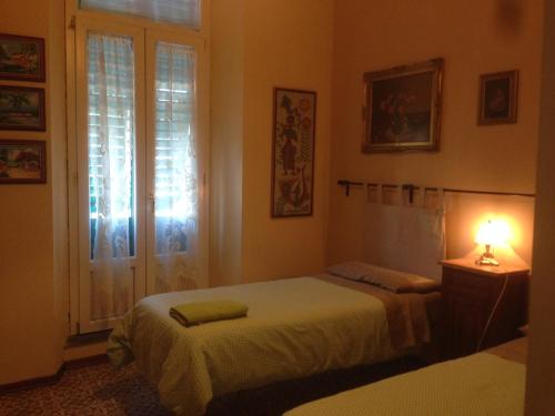1 dormitorio con 2 camas, lámpara y ventana en LA BARRIERA affittacamere, en Florencia