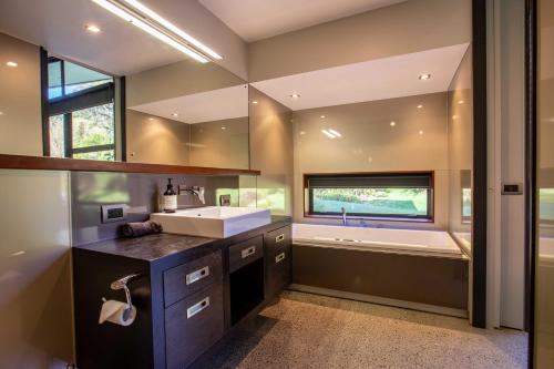 a bathroom with a sink and a bath tub with a window at The Jewel of Akatarawa in Upper Hutt