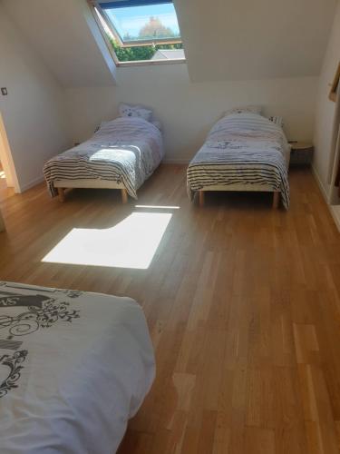 Dos camas individuales en una habitación con ventana. en Gîte Kerael de Tonquedec, en Tonquédec