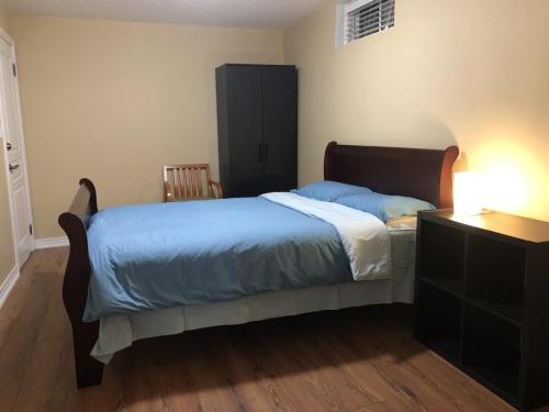 a bedroom with a bed with blue sheets and a dresser at Spacious 2 Bedroom guest suite in Toronto