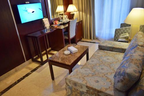 a living room with a couch and a tv at Romance Alexandria Hotel in Alexandria