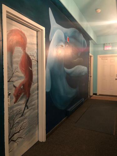 a hallway with a wall with a painting of birds at IceBerg Inn in Churchill
