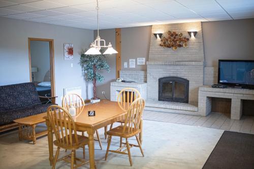 a living room with a table and chairs and a fireplace at Motel Et Condo Chez Charley in Sainte-Anne-de-Beaupré