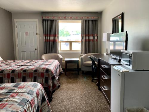 a hotel room with two beds and a desk with a microwave at Milestone Motel in Collingwood