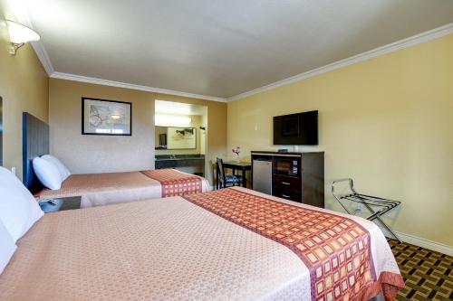a hotel room with two beds and a television at Hacienda Inn in La Puente