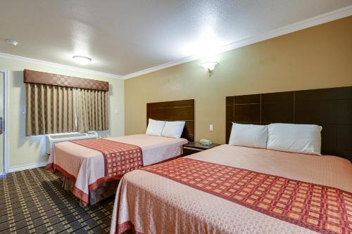 ein Hotelzimmer mit 2 Betten und einem Fenster in der Unterkunft Hacienda Inn in La Puente