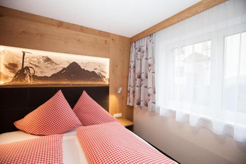 a bedroom with a bed with red and white pillows at Haus Küchelspitz in Ischgl
