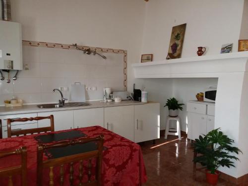 uma cozinha com armários brancos e uma mesa com uma toalha de mesa vermelha em Pinheiro da Chave em Melides