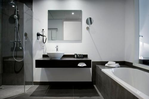 een badkamer met een wastafel en een bad bij Inntel Hotels Amsterdam Zaandam in Zaandam