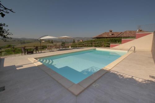 a large swimming pool in a patio with a table at Poggio dei Farinetti in Diano dʼAlba
