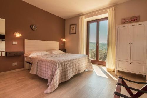 a bedroom with a bed and a large window at Poggio dei Farinetti in Diano dʼAlba