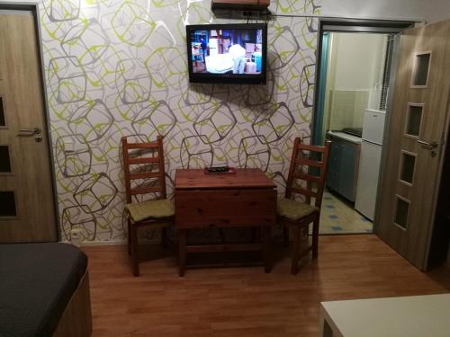 uma sala de estar com mesa e cadeiras e uma televisão na parede em Apartment Oltec em Bohunice