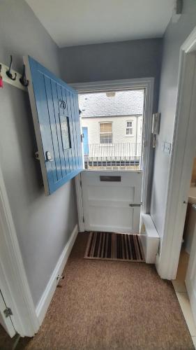 a hallway with a blue door and a window at Christie Cottage Trinity Mews in Torquay