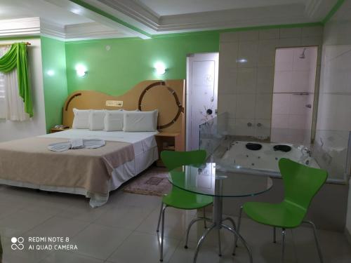 a bedroom with a bed and a tub with green walls at Hotel Lopes in Cubatão