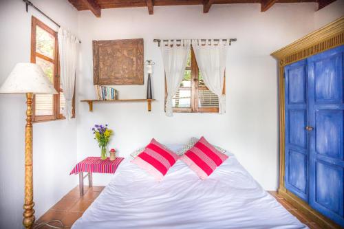 a bedroom with a white bed with two red pillows at Casa Paxanax in Santa Cruz La Laguna