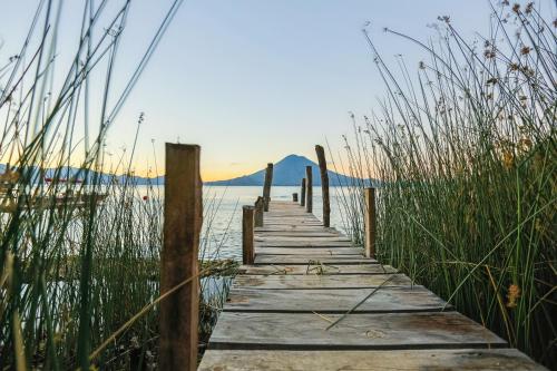a wooden pathway over the water with tall grass at Casa Paxanax in Santa Cruz La Laguna