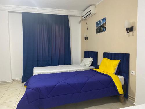 two beds in a room with blue and yellow at Hotel Métropole Résidence in Tunis