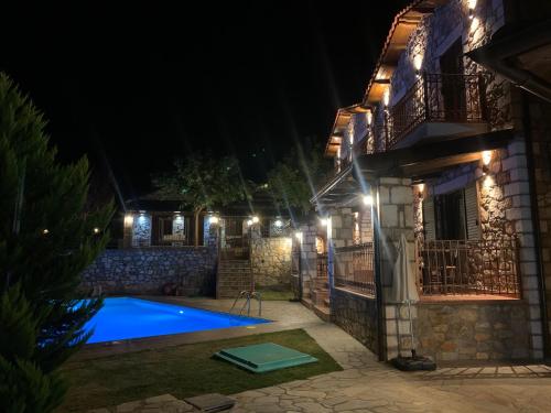 a villa with a swimming pool at night at Petrines Villes Avramilias in Avramiliá