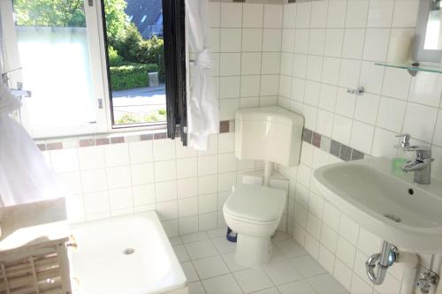a white bathroom with a toilet and a sink at FeWo Tilda in Garlstorf