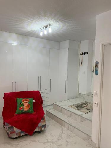 Cette chambre blanche dispose d'un oreiller rouge sur une chaise. dans l'établissement Cannes Apartment close to Congress Palace, Croisette, Beaches, à Cannes