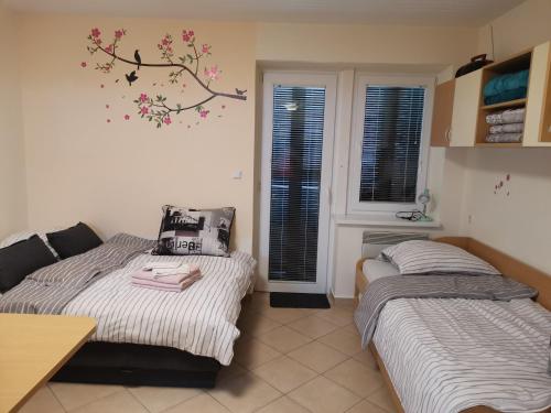 ein Schlafzimmer mit 2 Betten und einem Baumbild an der Wand in der Unterkunft Apartma Gaber 80 in Zreče