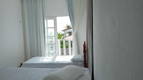 1 dormitorio con 2 camas y ventana grande en Pousada Solar di Poletti, en Nísia Floresta