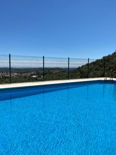 a large blue swimming pool with a fence in the background at El Molino de La Quinta in Constantina