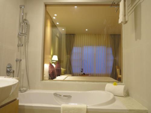 
a bathroom with a tub, sink and mirror at The Chancery Hotel in Bangalore
