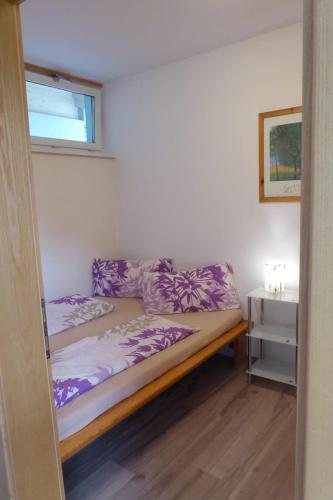 a bed in a room with purple sheets and a window at Ferienwohnung Mühlburger in Lienz