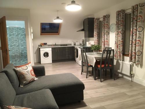 a living room with a couch and a table and a kitchen at Binnian View Apartment in Kilkeel