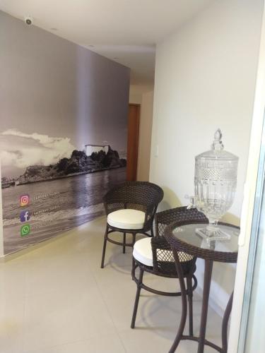 a dining room with a table and chairs and a painting at Summer Suítes - Passagem in Cabo Frio