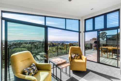 a living room with two chairs and a large glass window at Taonga with Sea Views by Waiheke Unlimited in Oneroa
