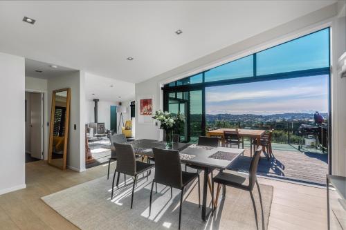 a dining room with a table and chairs and a large window at Taonga with Sea Views by Waiheke Unlimited in Oneroa