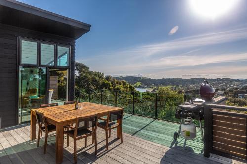 a house with a wooden table on a balcony at Taonga with Sea Views by Waiheke Unlimited in Oneroa