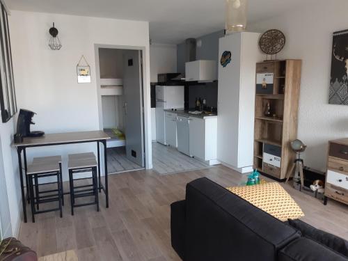 un salon avec un canapé et une table et une cuisine dans l'établissement Grand Appartement Luxe avec SAUNA et BAIN LED 50m de l océan avec belle terrasse pour manger CHIEN ADMIS 2 chambres pour 4 pers avec GRANDE BAIGNOIRE BALNEO SPA, à Biscarrosse