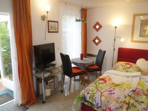 a bedroom with a bed and a table and a television at Bungalow Toscana - 350m zum Strand in Ostseebad Koserow