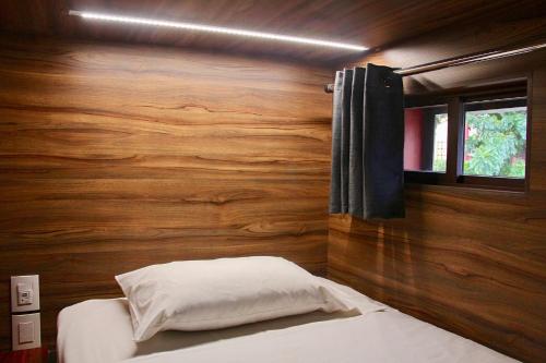 a bedroom with a wooden wall with a bed and a window at Casa Angel Hostel in Oaxaca City