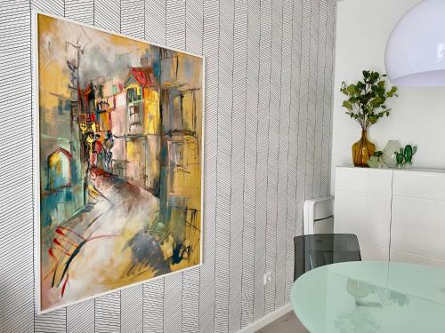 un dipinto appeso a un muro in una stanza con tavolo di modernes Apartment, Terrasse und Garten am Lilienthalpark im Südwesten Berlins a Berlino