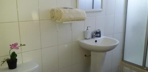 a white bathroom with a sink and a toilet at Hostal Tunquelen in Valparaíso