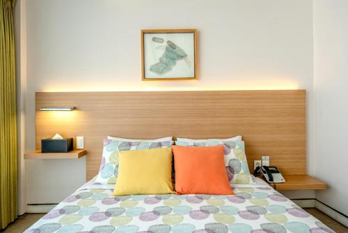 a bed with a wooden headboard and colorful pillows at Jeju Bom stay & Art Gallery in Seogwipo