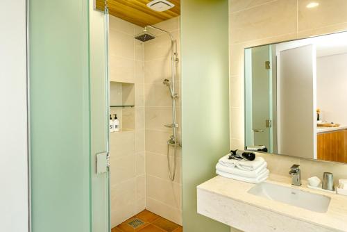 a bathroom with a shower and a sink and a mirror at Jeju Bom Museum stay in Seogwipo