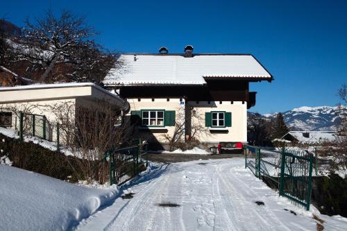 a house is covered in snow with a fence at Ferienhaus Kollinger in Kaprun
