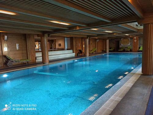 a large swimming pool with blue water in a building at Mountain view Private apartments in Pirin Golf and SPA resort in Razlog