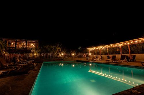 una piscina por la noche con sillas y luces en La Confianza Hotel, en Lunahuaná