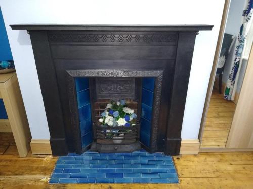 czarny kominek z niebieską podłogą wyłożoną kafelkami w obiekcie Cromer Guest House w mieście Bridlington