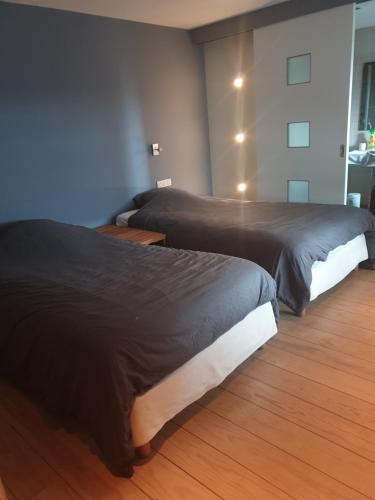 two beds in a room with wooden floors at Beautiful rooms at countryside Brussels in Halle